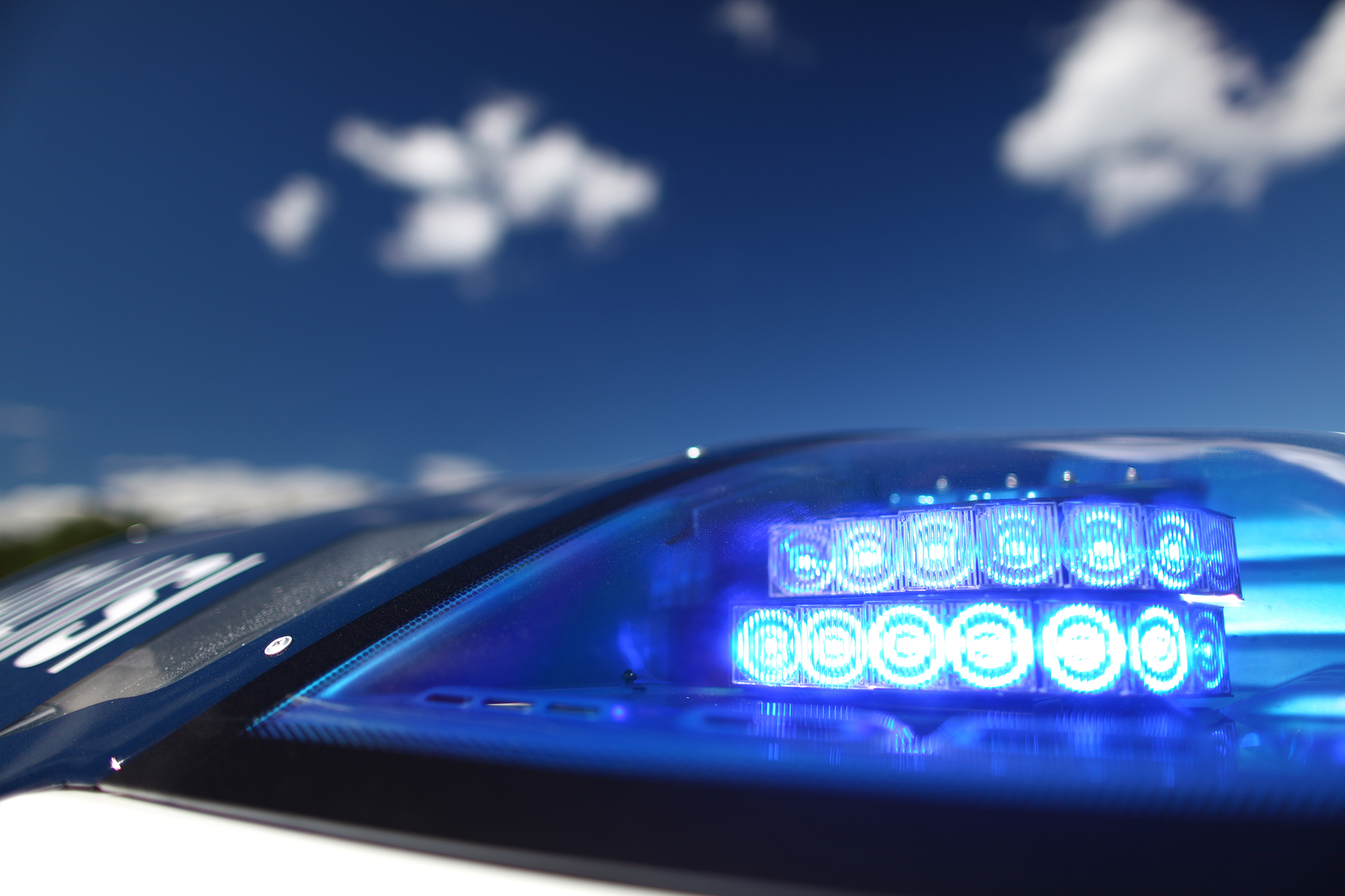 Poliisiauton vilkku lähikuvassa, taustalla sinistä taivasta. Kuva Poliisimuseo